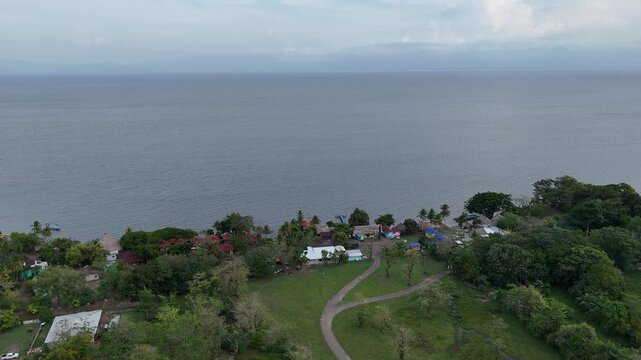 Drone flies toward Lake Izabal over the green grounds and tropical vegetation of Finca Paraiso near El Estor, Izabal, Guatemala.