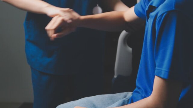 Doctor physiotherapist assisting a male patient while giving exercising treatment massaging the arm of patient in a physio room, rehabilitation physiotherapy concept