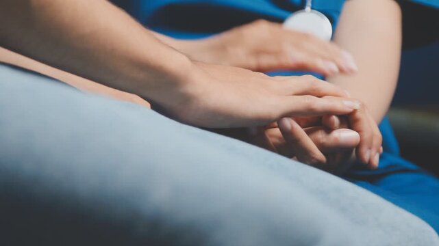 Doctor holding patient's hand on a white desk during medical consultation, offering support, empathy, care, reassurance, and compassion in a hospital or clinic setting