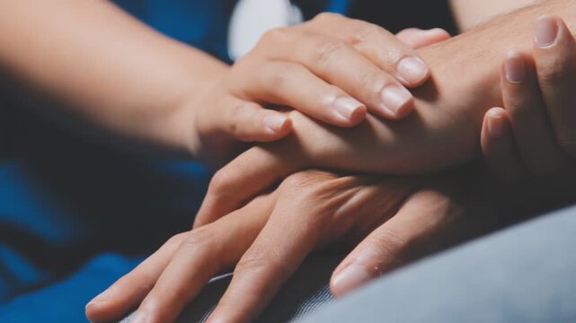 Doctor holding patient's hand on a white desk during medical consultation, offering support, empathy, care, reassurance, and compassion in a hospital or clinic setting