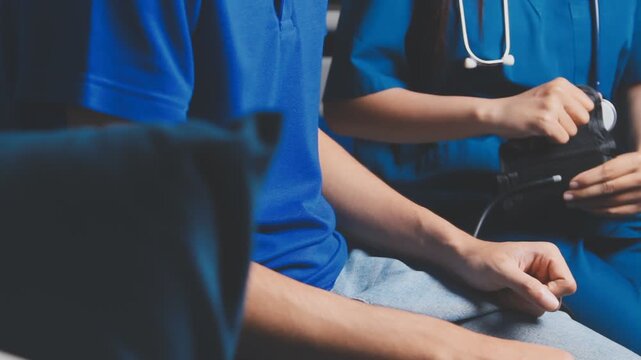 Female healthcare worker taking blood pressure on an adult male patient in a medical clinic, close-up with cropped faces