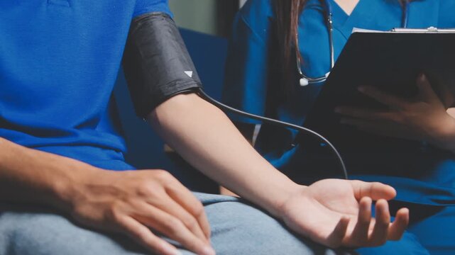 Female healthcare worker taking blood pressure on an adult male patient in a medical clinic, close-up with cropped faces