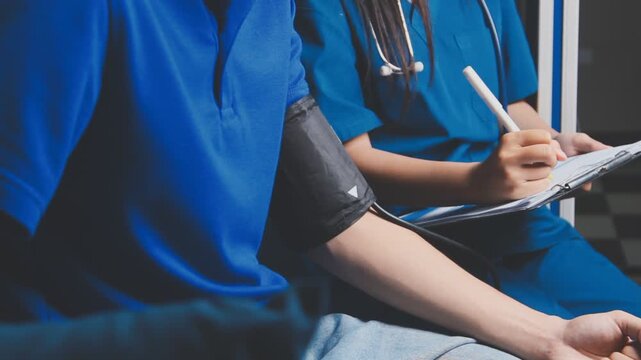 Female healthcare worker taking blood pressure on an adult male patient in a medical clinic, close-up with cropped faces