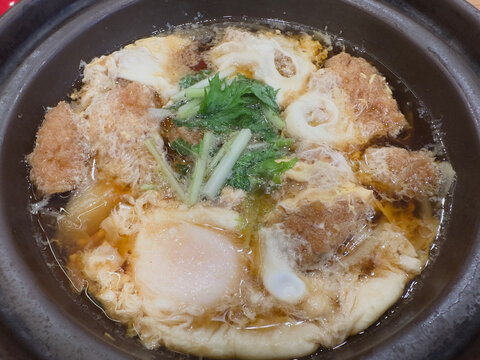 Katsu toji simmered pork cutlet with egg and mitsuba in a clay pot