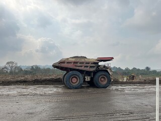 Heavy duty mining dump truck carrying overburden materials on haul road at open pit coal mine site © faaqiihh