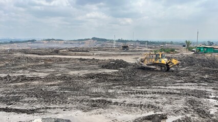 Yellow Bulldozer Operating and Clearing Land in Open Pit Coal Mine Area © faaqiihh