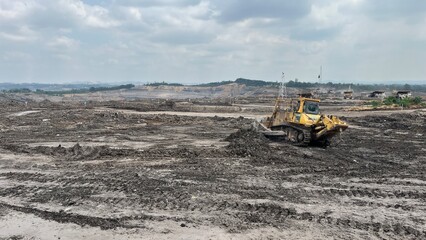 Yellow Crawler Bulldozer Clearing Terrain in Wide Open Pit Mine Site © faaqiihh