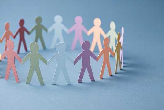Diverse group of paper people holding hands in a circle representing unity and connection