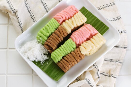 Top View of Colorful getuk lindri, a traditional Indonesian cassava cake, arranged with grated coconut on a white plate and banana leaf for an authentic culinary presentation.
