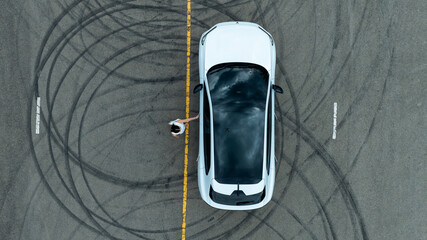 Woman stands near ev car. She poses by white ev car. Stylish ev car on road. © Nutchanart