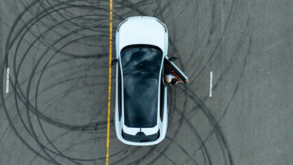 Woman stands near ev car. She poses by white ev car. Stylish ev car on road. © Nutchanart