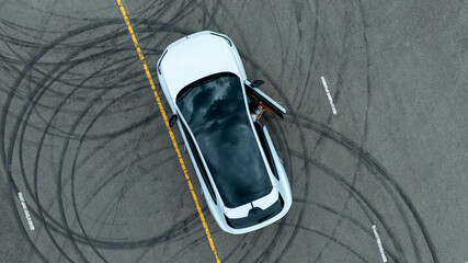 Woman stands near ev car. She poses by white ev car. Stylish ev car on road. © Nutchanart