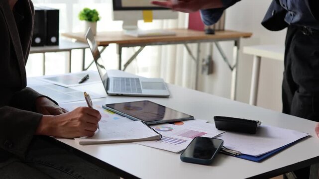 Business colleagues collaborating on a financial project, analyzing charts and data on documents and a tablet during a productive office meeting and brainstorming session