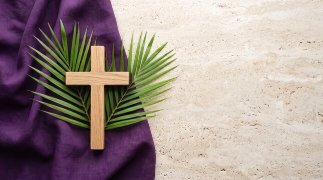 Wooden cross with green palm leaves on purple fabric and light beige stone surface for religious holiday background