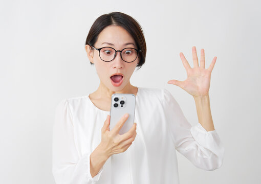 スマホを見て驚くミドル女性　白背景