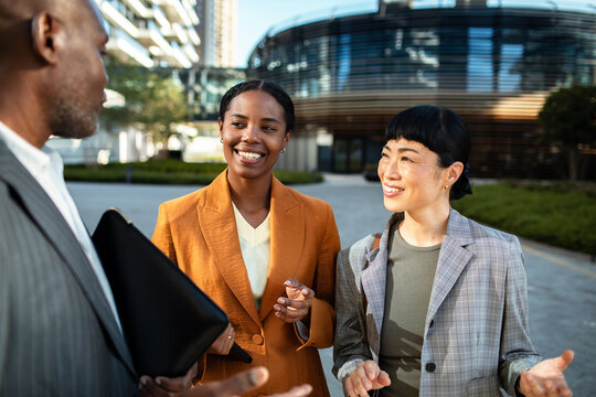 Diverse business colleagues networking outside modern office