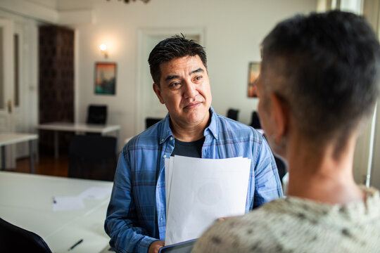 Coworkers discussing documents in modern office
