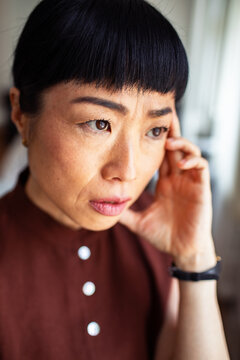Concerned woman touching temple at home