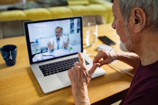 Senior man having virtual doctor consultation at home on laptop