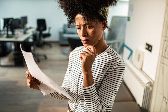 Concerned woman reviewing document in modern office