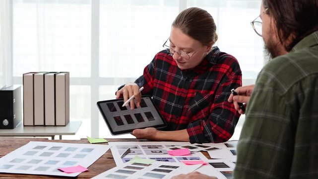 Creative female designer discussing a mobile app user interface design with a colleague, brainstorming ideas and collaborating on the ux ui development project in the office