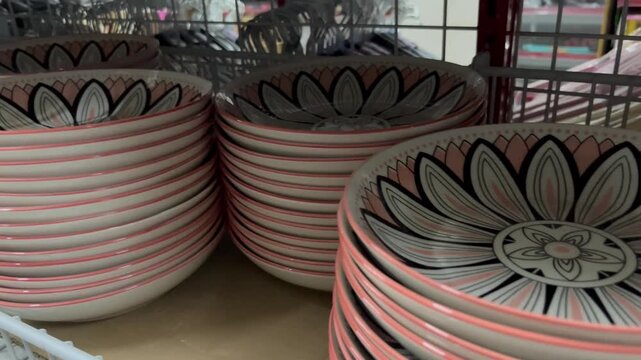 Stack of pink ceramic bowls with floral pattern on display in a shop