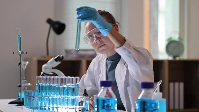 Female scientist mixing chemical reagents in a test tube and analyzing samples during a clinical research experiment in a modern laboratory for medical development
