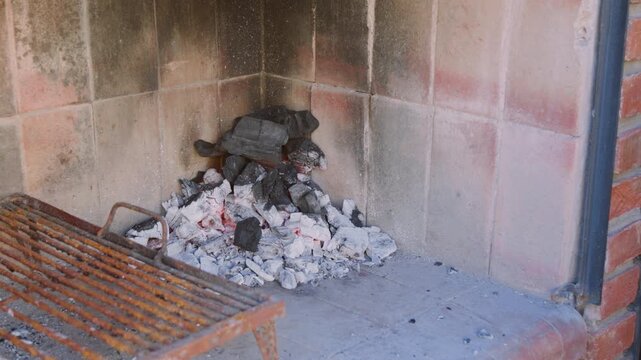 Man Fanning Embers to Start a Fire for a Traditional Argentine Asado in a Brick Parrilla, 4K
