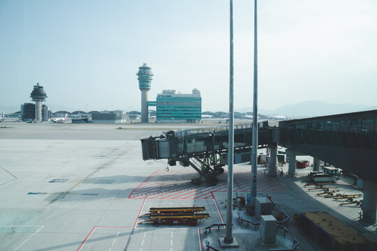 HONG KONG - DECEMBER 3, 2017: Passenger boarding bridge on the tarmac with control tower view at Hong Kong International Airport.