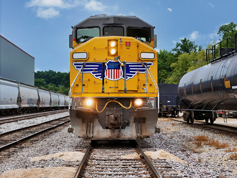 Front view of Train Locomotive Charging Forward Through Industrial Rail Yard