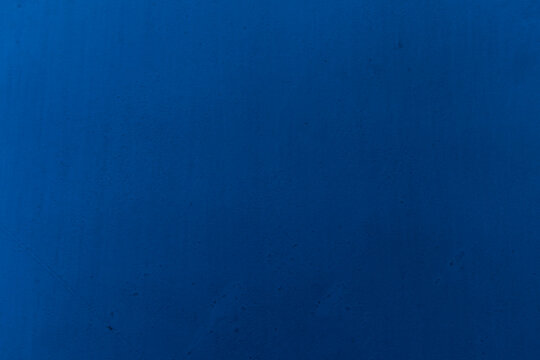 Dark blue uneven cement wall textured as background. Retro old plaster sand grungy worn rough painted surface. closeup view. Minimalist coarse concrete texture backdrop with copy space.  