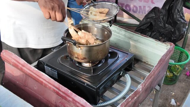 Freshly fried snacks are lifted from sizzling oil to drain, perfectly crispy and ready for eager customers.