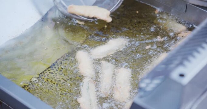 熱い油の中で衣がサクサクに揚がっていくズッキーニのフライの調理クローズアップ動画