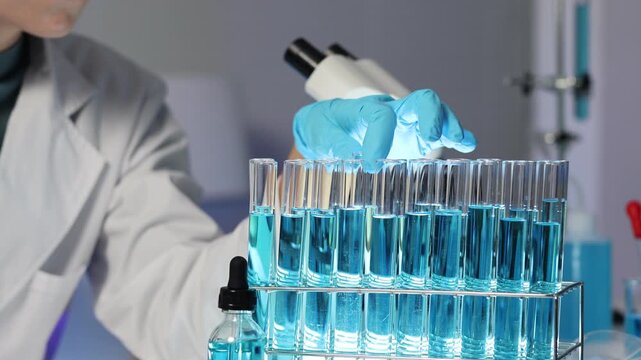 Young scientist pipetting blue liquid into test tubes during a chemistry experiment in a medical research laboratory for scientific innovation and vaccine development