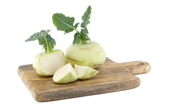 Fresh kohlrabi bulbs and wedges on a rustic wooden cutting board