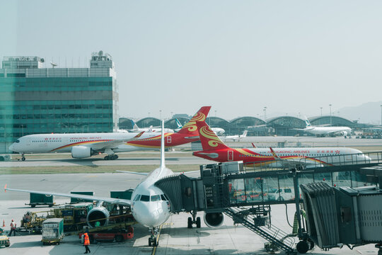 HONG KONG - DECEMBER 3, 2017: Hong Kong International Airport. Hong Kong Airlines aircraft passenger jetliners parked at the boarding gate terminal and taxiing on the airfield apron during daytime gro