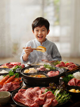 Joyful moment of an Asian boy having fun while sharing a hot pot meal with family
