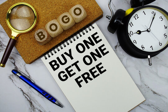 BOGO Buy One Get One Free text written on notepad with calculator and magnifying glass on marble background