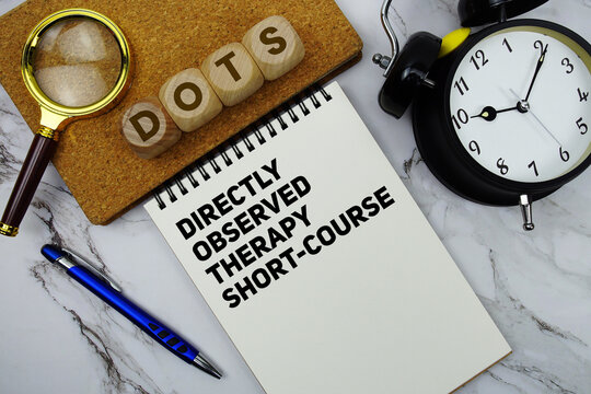 DOTS Directly Observed Therapy Short-course text written on notepad with calculator and magnifying glass on marble background