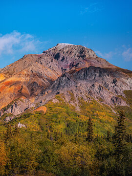 Sheep Mountain in the eastern Talkeetna Mountains along the Glenn Highway in Matanuska Glacier Alaska with vibrant red, orange and yellow volcanic mineral layers on the cliffs