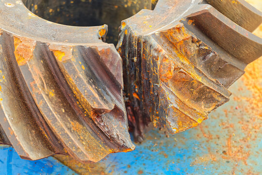 Spiral bevel gear of engine transmission in damaged and cracked condition due to heavy duty used. Industrial equipment object, close-up with selecive focus.