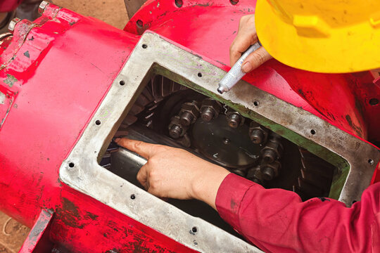 Action of an engineer is using chemical to check on spiral bevel gear contact between gear's teeth during inspection the engine transmission part. Industrial working scene, close-up with selective foc
