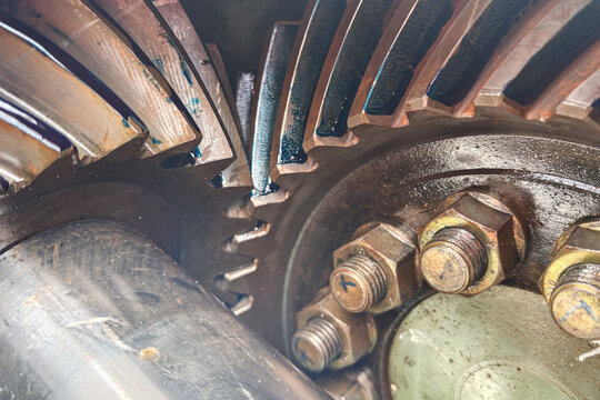 Heavy-duty spiral bevel gear assembly meshing together, featuring detailed teeth contact patterns with blue lubrication dye on the mechanical component. Industrial machine equipment part, close-up wit