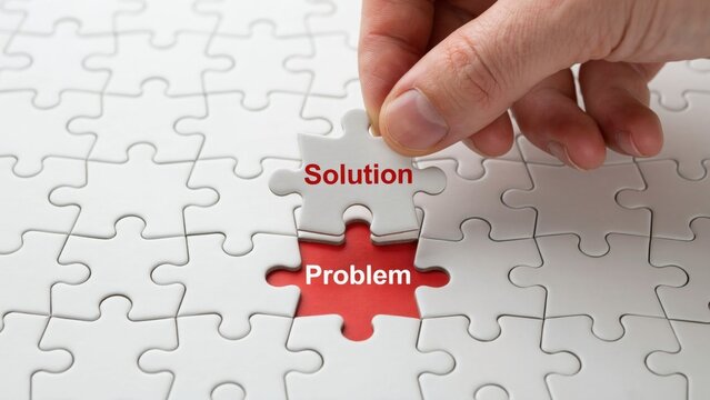 Human hand placing a white jigsaw puzzle piece labeled solution over a red base area representing a difficult business problem