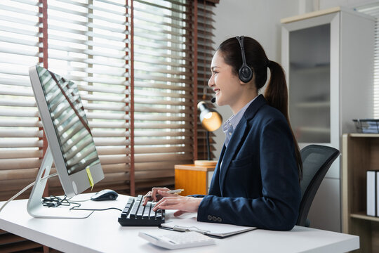 Asian woman assisting clients wearing headset at desk