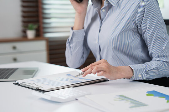 Woman analyzing financial report data while talking on phone