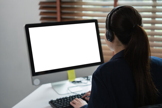 Woman wearing headset working at computer with blank screen