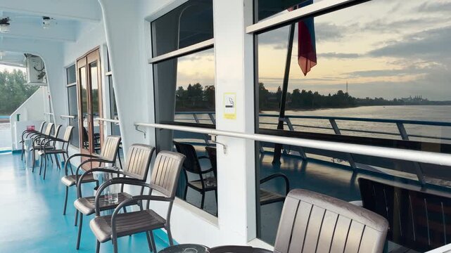 A modern cruise ship sails peacefully along the Neva River. Passengers relax on the open deck, enjoying the calm atmosphere. The serene journey brings a feeling of happy tranquility.
