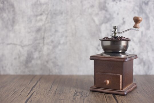 Manual coffee grinder with coffee beans on modern background