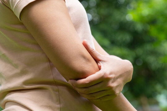 A woman has pain in his elbow and tendon muscles and he relieves the pain with a massage. Health and healing concept	
